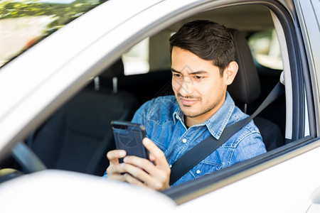 坐在停着的汽车里在手机上发短信的图片