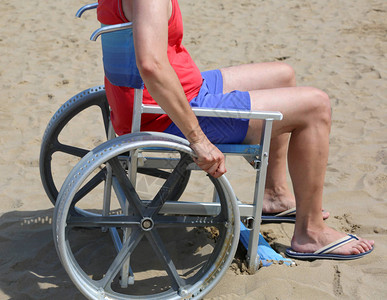 年轻人坐在轮椅上在沙滩上的沙子上图片