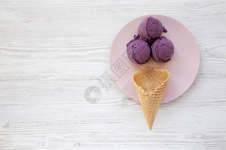 白色木质表面的粉红色板块上有甜冰淇淋锥和冰淇淋勺图片