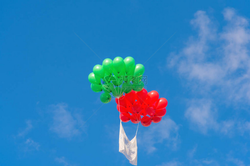 一群红色和绿色的气球飞向蓝天图片