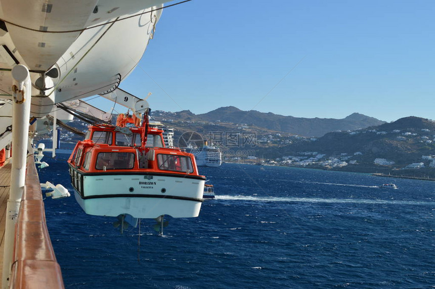 MikonosIslandindiffused背景的游轮上载有Mykonos岛的救生艇图片
