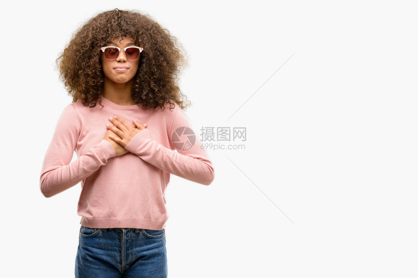 身戴粉红色太阳镜的非洲美妇女用双手在胸前微笑图片