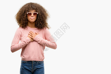 身戴粉红色太阳镜的非洲美妇女用双手在胸前微笑图片