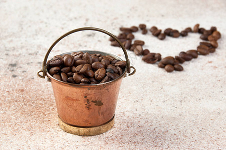 装满咖啡豆和咖啡豆心脏形状的旧铜桶图片