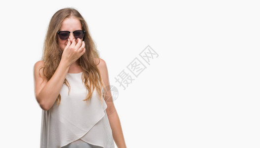 身戴太阳镜的金发年轻女子闻到臭味恶心无法忍受的气味图片