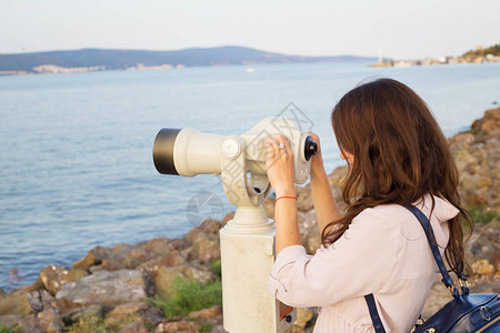 女孩透过望远镜看海图片