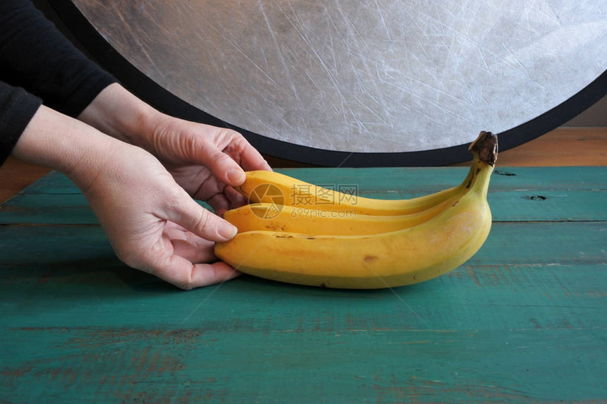 食物摄影师在摄影棚的木板背景上拍摄一帮新鲜香蕉图片