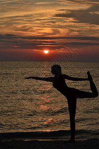 日出时女剪影从瑜伽中的战士姿势图片