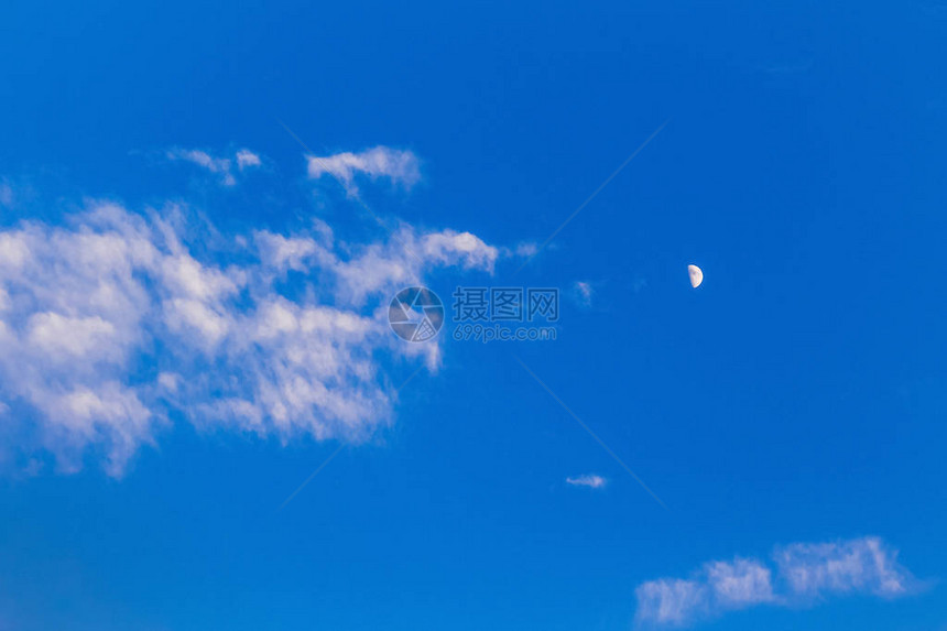 蓝色傍晚天空上的月亮和白云图片