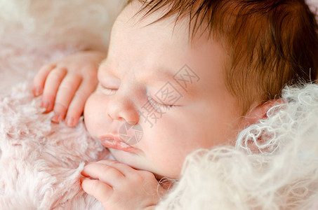 新生婴儿特写睡在柔软蓬松的毯子上图片