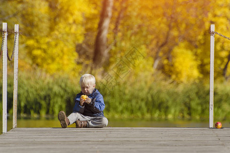 金发小男孩在码头吃苹果秋图片