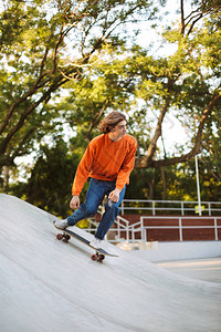 参加橙色滑轮板和练习特技的年轻人在现代滑背景图片