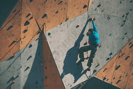 人工浮雕上的登山者一个人爬上攀岩墙在街头攀岩墙上训练为比赛图片