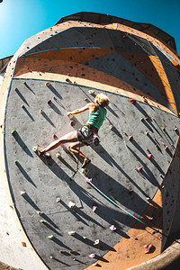 登山者在人工浮雕上训练一名妇女在街道攀岩墙上攀登岩路线在大厅训图片