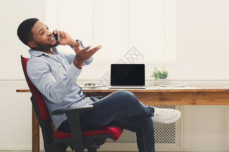 年轻的非洲美国商人通过电话在现代办公复印空间进行电话交谈商业咨图片