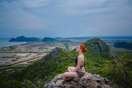 快乐的女徒步者坐在悬崖上图片