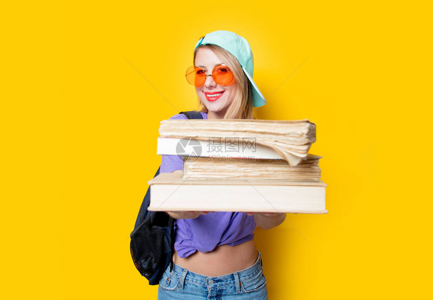 带橙色眼镜和黄色背景书籍的年轻时装女学生女孩图片