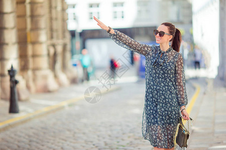年轻女孩在欧洲城市的一条小街上搭计程车图片