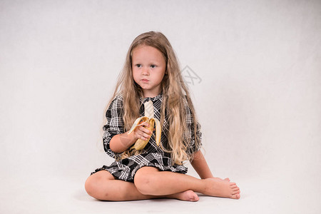 美丽的可爱的小女孩吃美味健康的香蕉白色图片