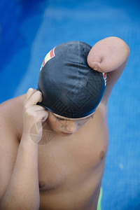 游泳的年轻男孩他没有手臂残疾人他戴图片