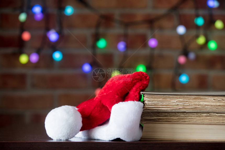 圣诞老人帽子和木桌上的书背景有图片