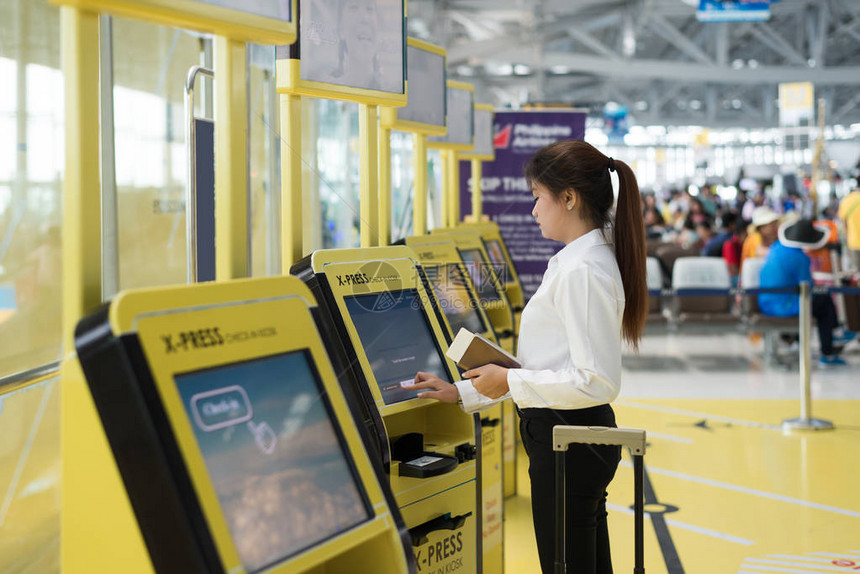 年轻的亚洲女商人在机场使用自助值机图片