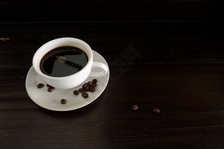 树桌上的咖啡杯和咖啡豆供图片
