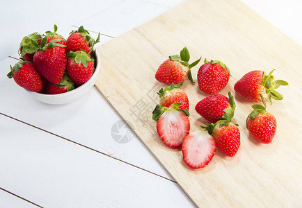 大碗里的红草莓放在木托盘旁边图片