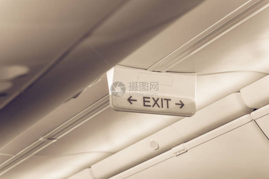 飞机天花板上带有红色箭头的复古色调紧急出口标志顶部隔间下方的发光疏散符号闪亮的招牌展示紧急紧图片