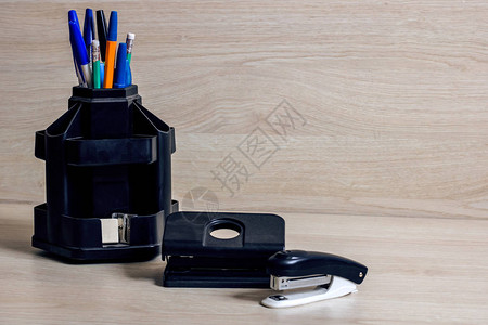 黑色支架订书机和打孔器中的钢笔和铅笔背景图片