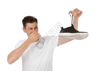 男人在白色背景的鞋子里闻到难闻的气味空气清新剂图片