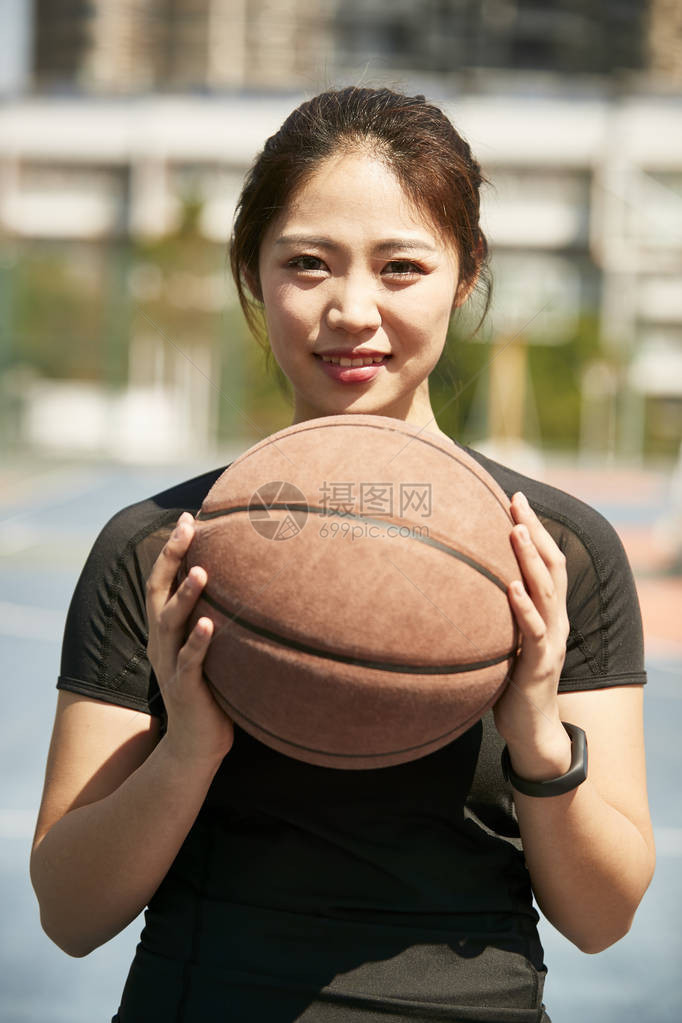 年轻女士拿着篮球看着摄影机笑着图片