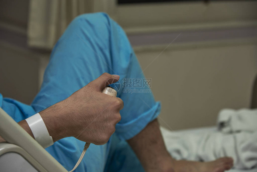一个穿蓝衬衫的病人躺在床上按下键图片