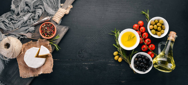 橄榄橄榄油奶酪和香料黑木背景的图片