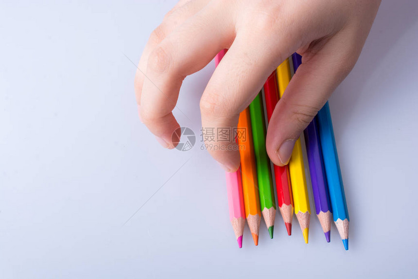 手持彩色铅笔放在白色背景上图片