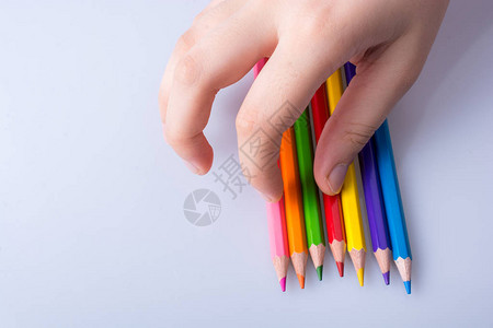 手持彩色铅笔放在白色背景上图片