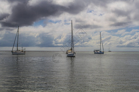 三艘帆船在阴云的图片