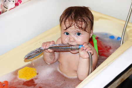 用蓝眼睛和姜发坐在婴儿浴缸里小可爱的小孩在玩具泡沫和乳图片