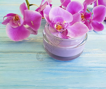 蓝色木质背景上的奶油化妆品兰花图片