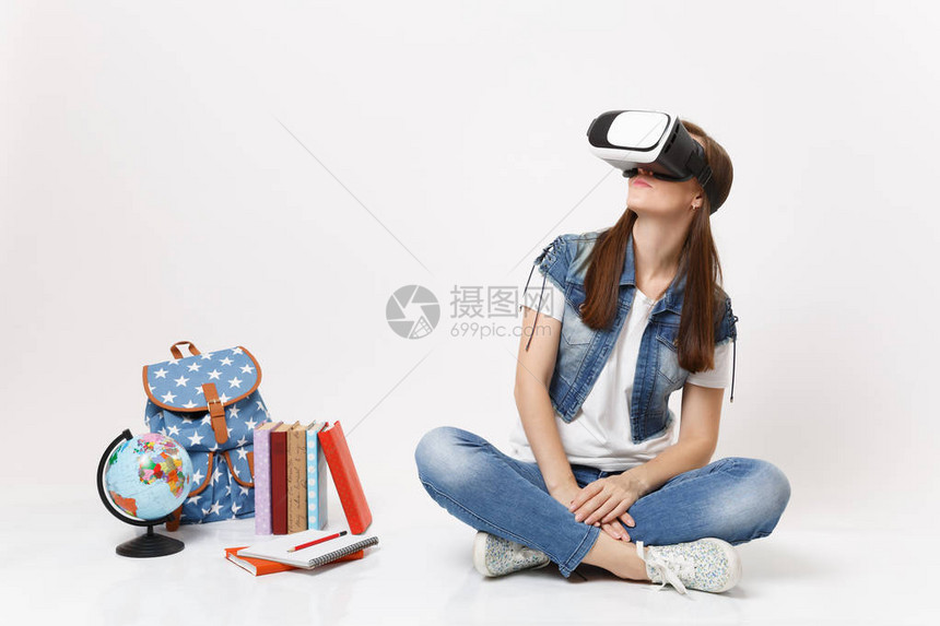 戴着虚拟现实眼镜的年轻黑发女学生一边看一边享受坐在地球附近背包孤立在白色背景上的课本学校大学院图片