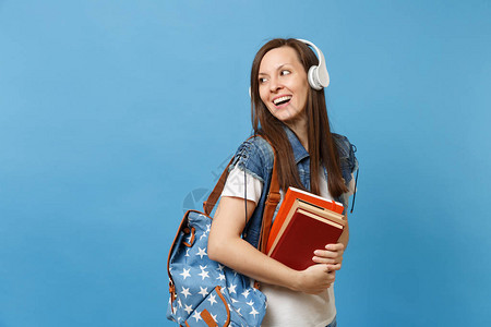 带着背包耳机听音乐的年轻好奇女学生的肖像拿着课本图片