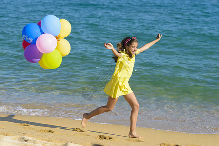 快乐的女孩拿着气球在沙滩图片