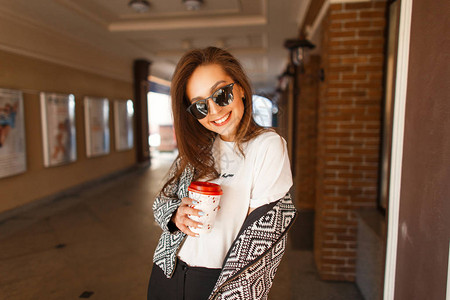 年轻快乐的女士微笑在时尚的太阳镜里穿着时髦的轰炸机夹克在城里图片
