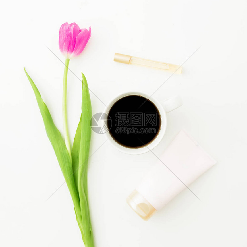 由郁金香花组成咖啡和化妆品的杯子在白色背景上隔图片