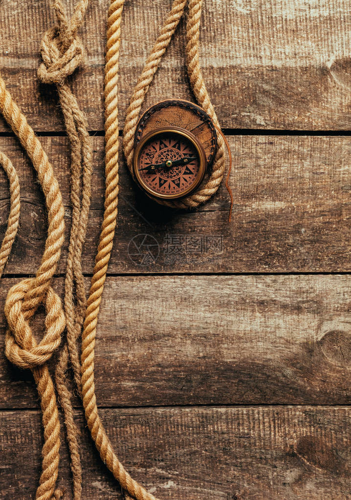木制背景上的船绳和指南针图片