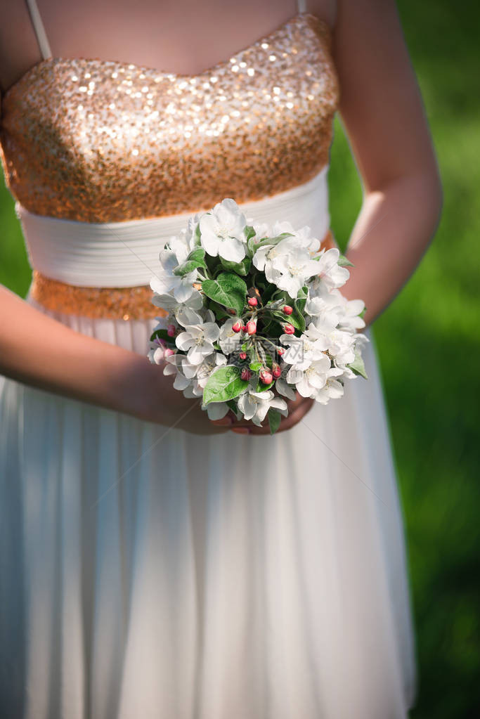 白花束花在优雅的女子手中一个穿浅图片