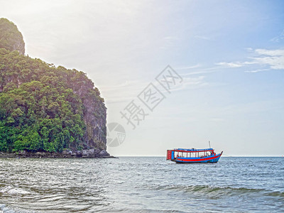 当地旅游客轮渡船在靠近岩石山的海面上图片