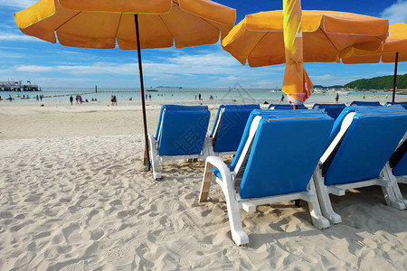 一排沙滩椅是五颜六色的黄色雨伞图片