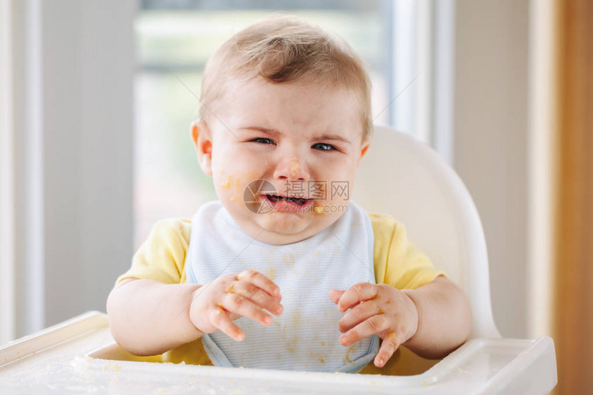 用手指吃苹果泥后坐在高脚椅上的可爱哭泣的白人小男孩的肖像日常童年生活方式婴儿尝试图片