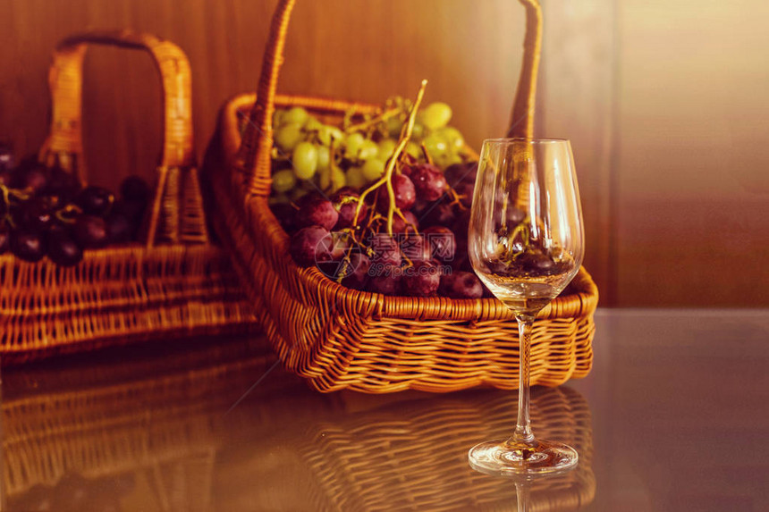 餐桌上放着一杯白葡萄酒和篮子里的葡萄图片
